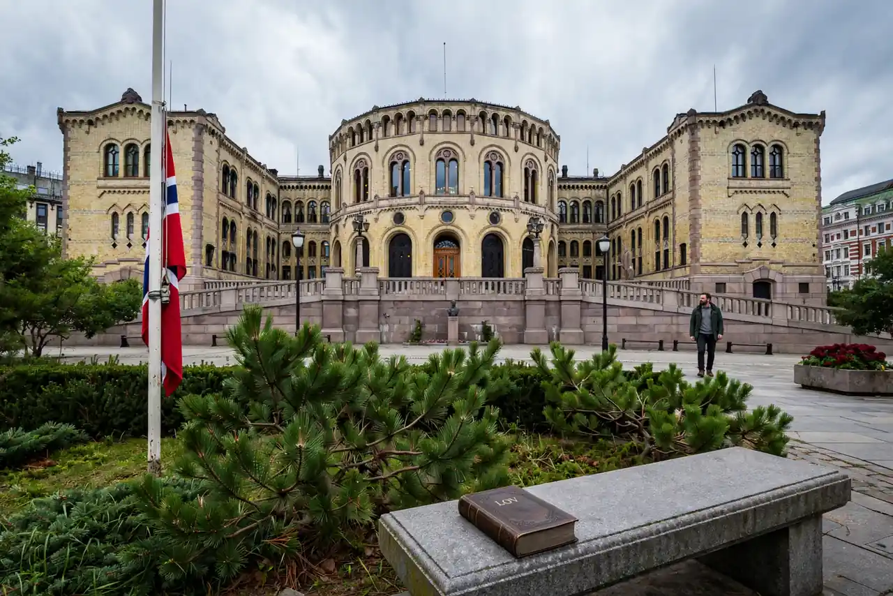 Stortingsbygningen i Oslo med norsk flagg og en lukket lovbok